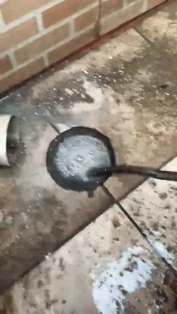 Ralo externo voltando a escoar enquanto o cabo da máquina desentupidora trabalha dentro da tubulação